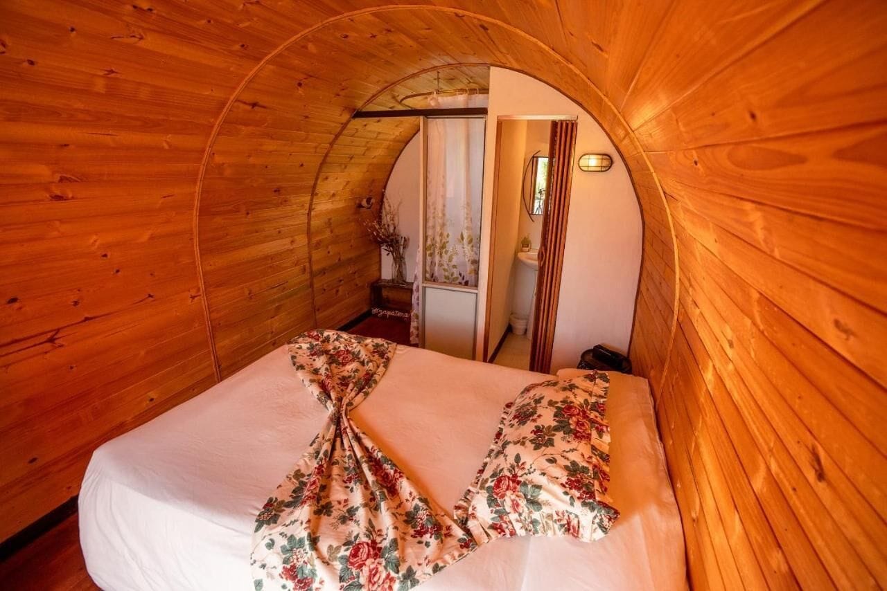 A cozy, wooden-paneled room with a bed featuring floral bedding.