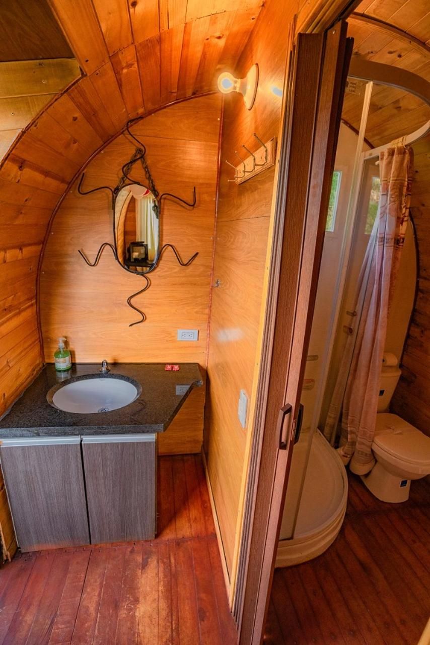 Un baño de madera pequeño y funcional con lavamanos, espejo y retrete.