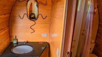 Un baño de madera pequeño y funcional con lavamanos, espejo y retrete.