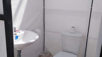 A small, compact bathroom with a white sink, toilet, and trash bin.