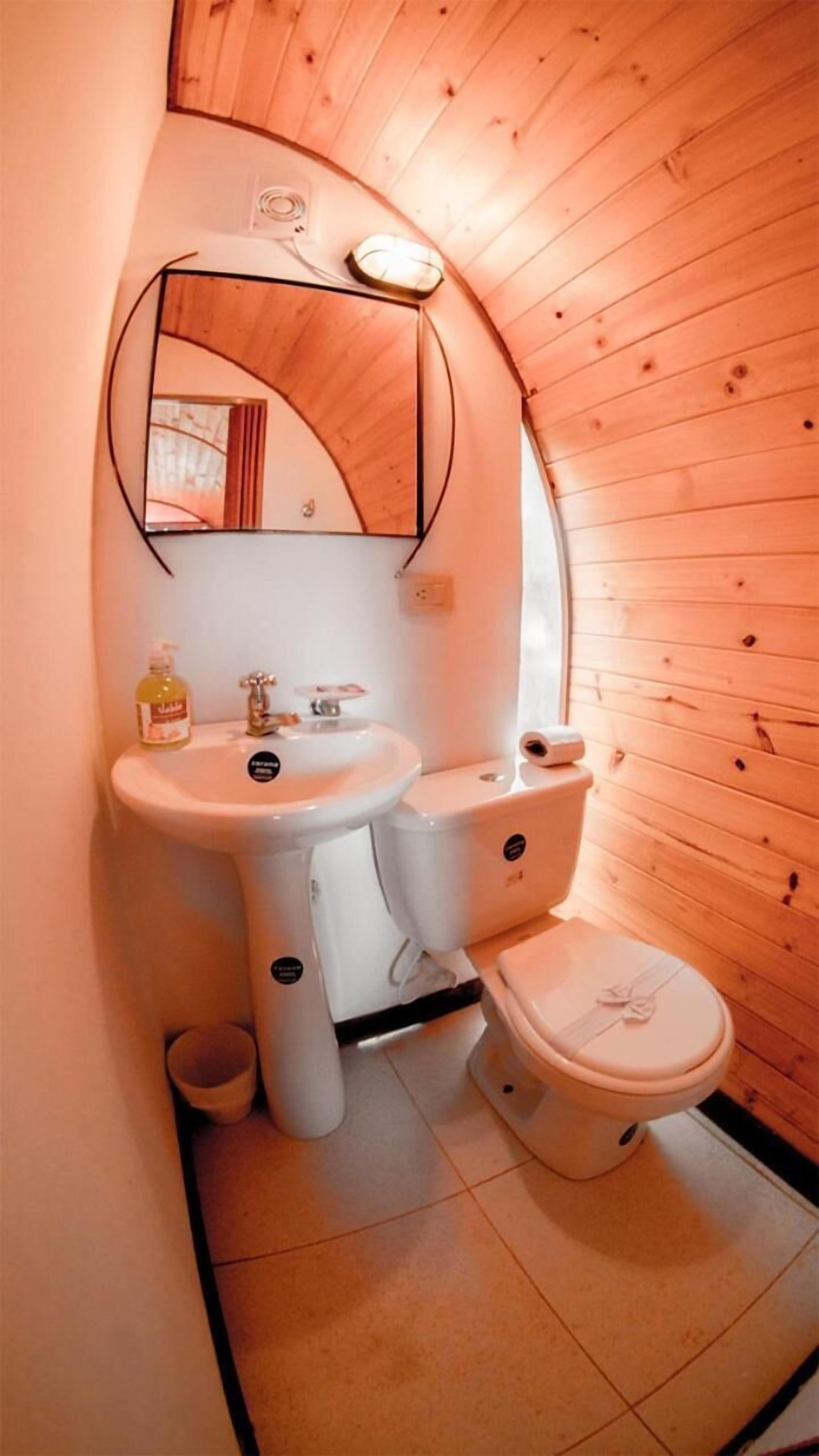 A compact bathroom with a sink, toilet, and mirror.