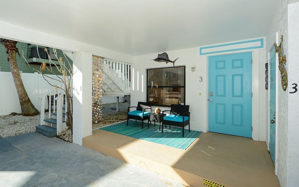 A property with a blue door, a staircase, a seating area with two chairs, and a small table.