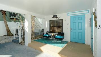 A property with a blue door, a staircase, a seating area with two chairs, and a small table.