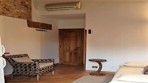 Una habitación con cama, una silla, una mesita y una puerta.
