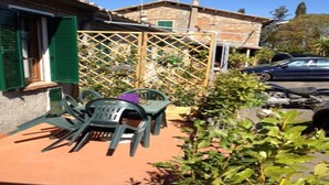 Un patio con mobiliario exterior, una valla de madera y un coche estacionado.