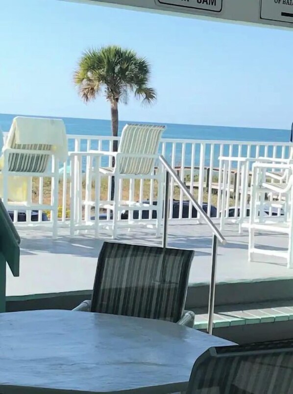 A beachside seating area with white chairs and a table, overlooking the ocean.