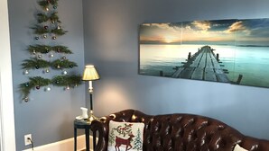 A living room with a brown leather sofa, a Christmas tree, a lamp, and a painting of a pier. - Downtown Lebanon, Near Kings Island, Lovely Historic Home, 1st Flr, Washer/Dryer (Lebanon)
