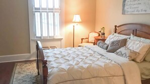 A bedroom with a bed, a nightstand, a lamp, a chair, and a wall with a quote. - Downtown Lebanon, Near Kings Island, Lovely Historic Home, 1st Flr, Washer/Dryer (Lebanon)