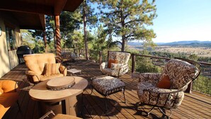 Une terrasse extérieure couverte, offrant une vue sur un paysage montagneux, et aménagée avec un canapé, des fauteuils et une table.