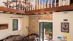 Ein geräumiges Wohnzimmer mit hoher Decke, Holzbalken, einem Kamin und einem Balkon mit Steinwand.
