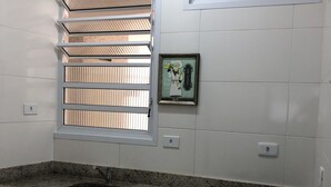 A kitchen with a granite countertop, a sink, and a gas stove. There are two windows with blinds, and a framed picture on the wall.