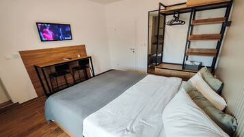 Un dormitorio con cama, escritorio y televisor montado en la pared.