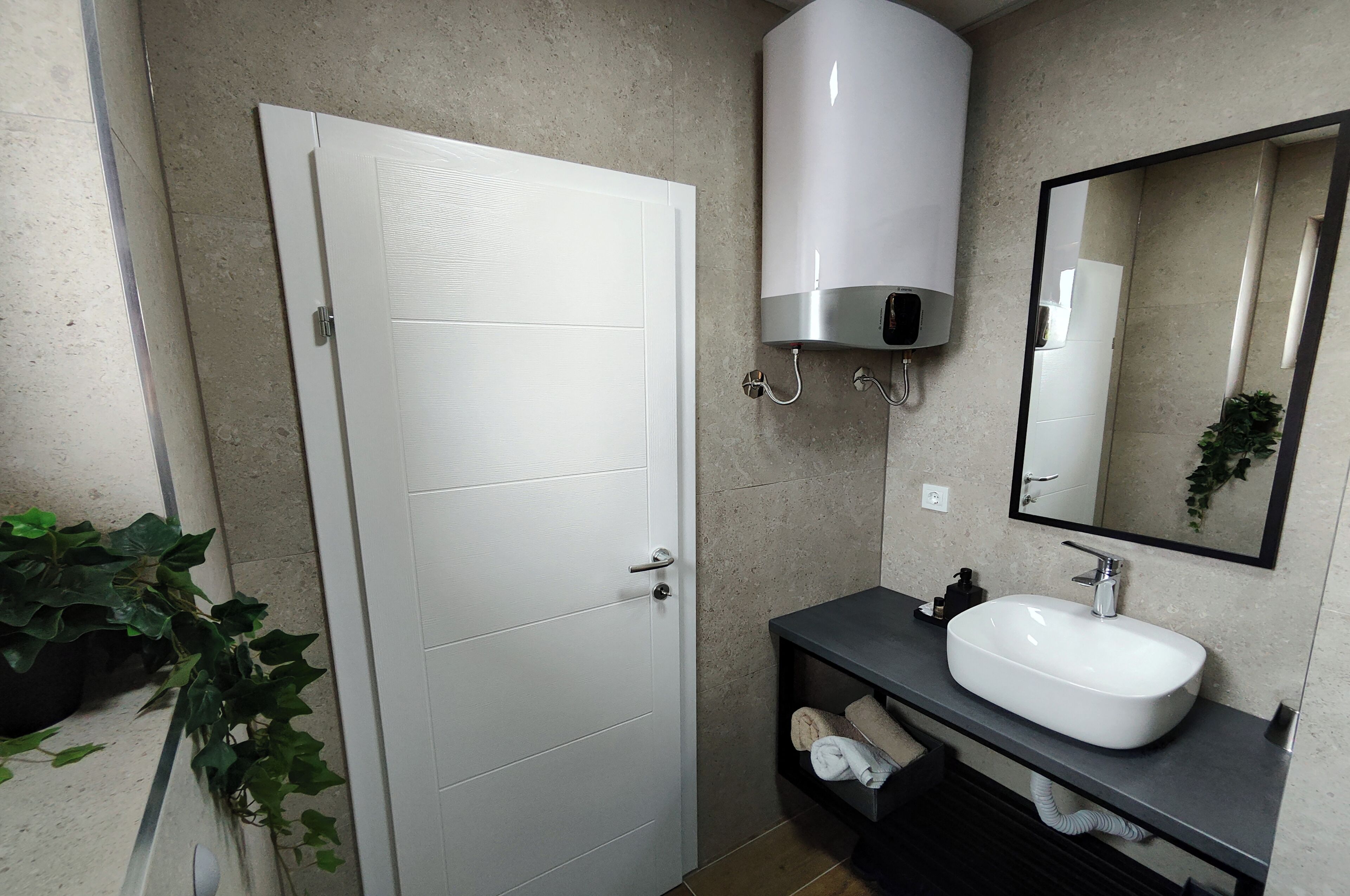 A bathroom with a white door, a white sink, a mirror, and a towel rack.