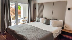 Et hotelværelse med en stor seng, udsigt til balkonen udenfor og en moderne aircondition.