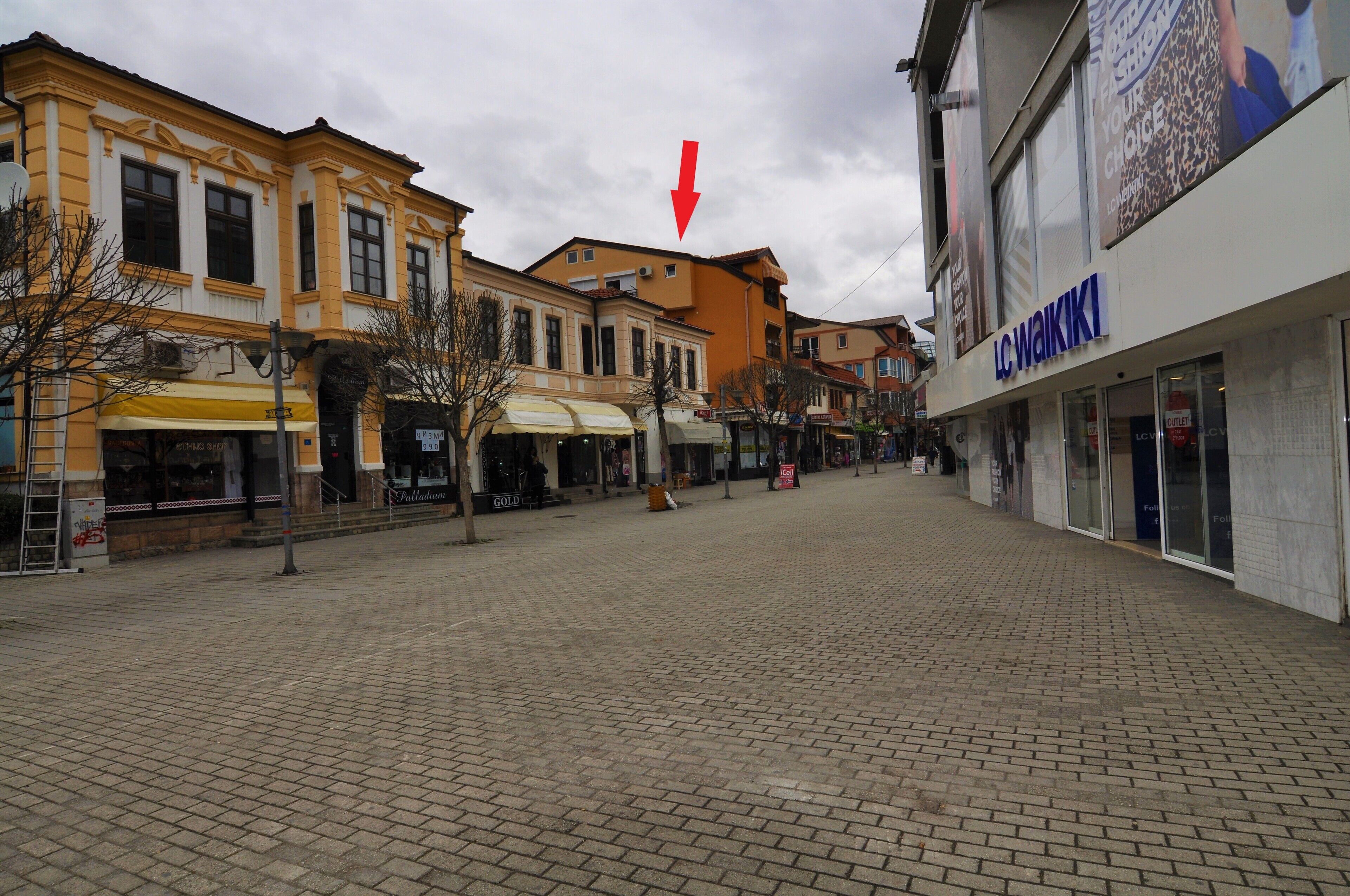 Ein gepflasterter Platz mit Gebäuden an beiden Seiten, darunter ein Geschäft namens LC Waikiki.