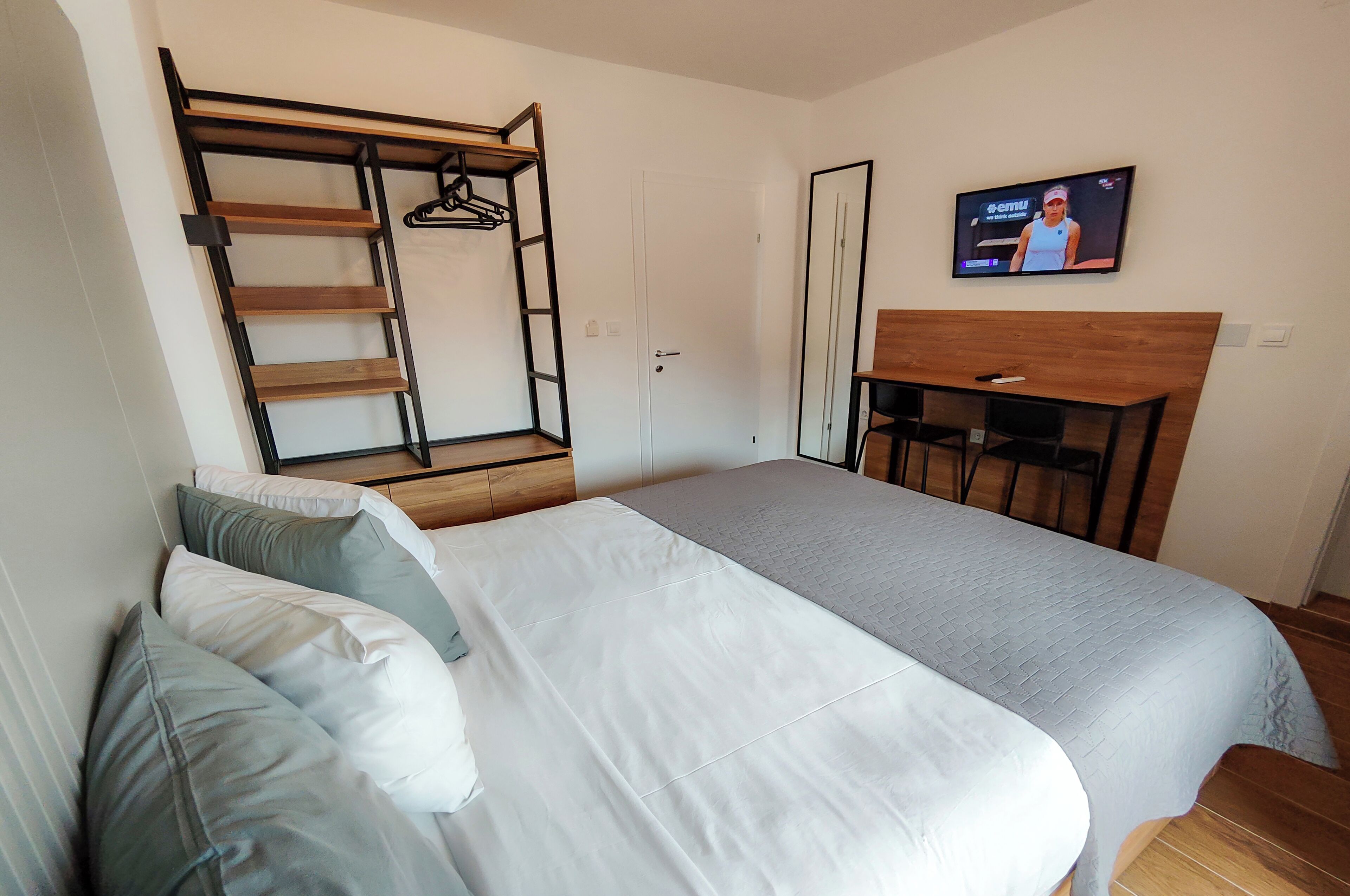 Un dormitorio con una cama, un escritorio, un televisor y un armario.