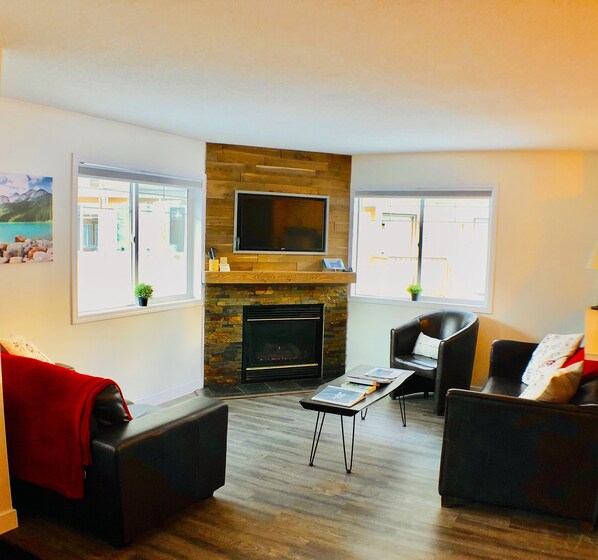 Una sala de estar con chimenea, dos sofás de cuero, una mesa de centro y un televisor de pantalla plana montado en la pared.