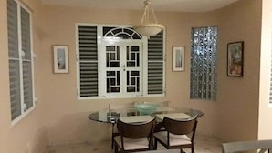 Un comedor con una mesa de vidrio redonda, cuatro sillas y una lámpara colgante.
