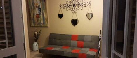 A living room with a grey sofa, a wall-mounted decorative piece, and a painting.
