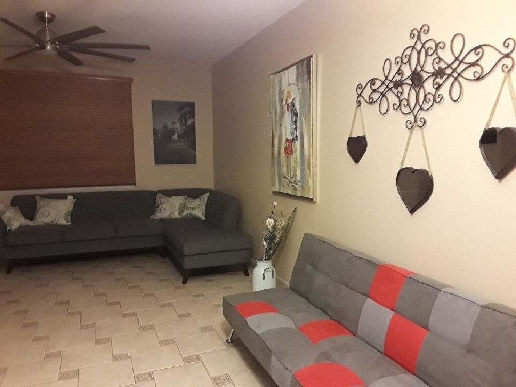 Ein Wohnzimmer mit zwei Sofas, einem Deckenventilator, Wandbildern und dekorativen Wandgestaltungen.
