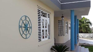 Un edificio moderno con techo plano, un porche cubierto con pilares azules y una brújula decorativa en la pared.