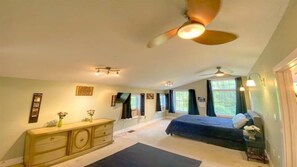 Relax in this serene bedroom with a large bed, ceiling fan, and natural light pouring in through the windows.