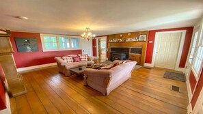 Relax in a spacious living room with a comfortable sofa set, armchair, and coffee table, featuring a fireplace and chandelier.