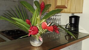 Uma cozinha com bancada de vidro, um vaso com flores e armários de madeira.