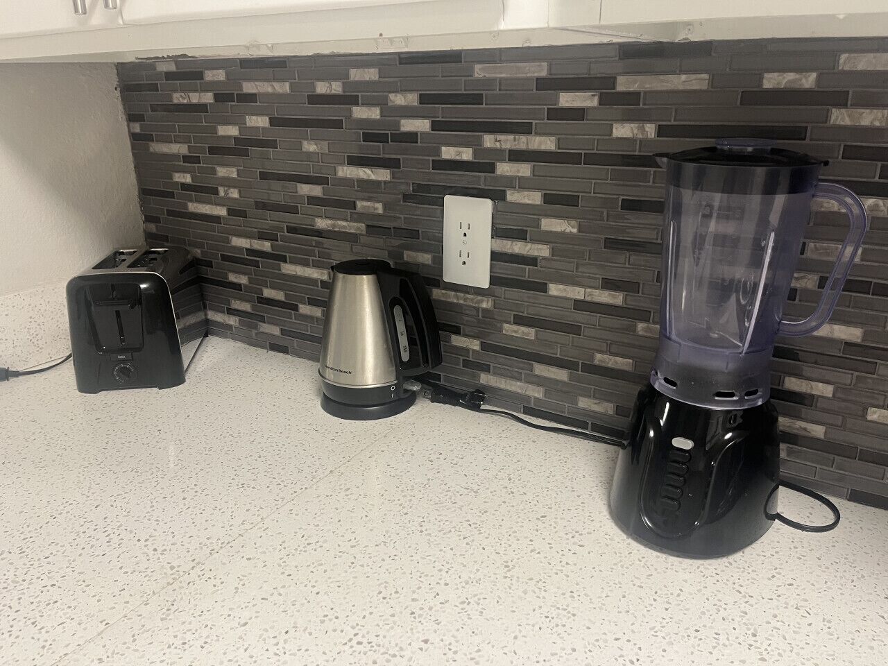 Una cucina con un piano di lavoro, un tostapane, una macchina da caffè e un frullatore.