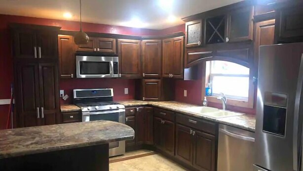 Una cocina moderna con armarios de madera oscura, electrodomésticos de acero inoxidable y encimera de granito.