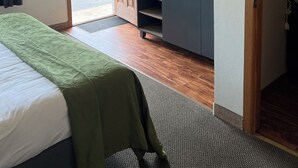 Una habitación de hotel con cama, escritorio, televisor y puerta que da al exterior.