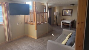 Una sala de estar con televisor, escalera, comedor y sofá.