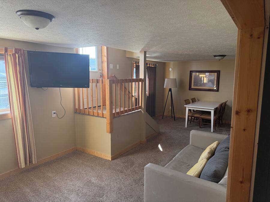Una sala de estar con televisor, escalera, comedor y sofá.