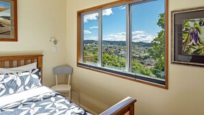 Ein Schlafzimmer mit großem Fenster und Blick auf Stadt und Grünflächen.