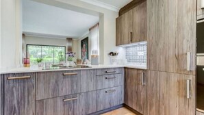 Una cocina con armarios de madera, una encimera y un ventanal con vistas a zonas verdes.