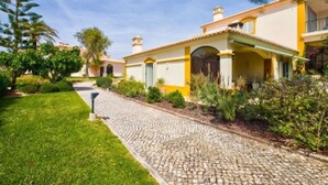 Una casa con camino de entrada pavimentado, césped cuidado y cielo despejado.