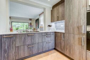 Eine Küche mit Holzausstattung, einer Arbeitsplatte und einem Fenster mit Blick auf Grünflächen.