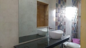 A bathroom with two sinks, a mirror, and a shower area. - Aapni Haveli (Jaisalmer)