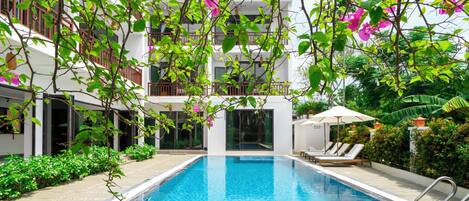 Una piscina al aire libre, sombrillas, sillones reclinables de piscina