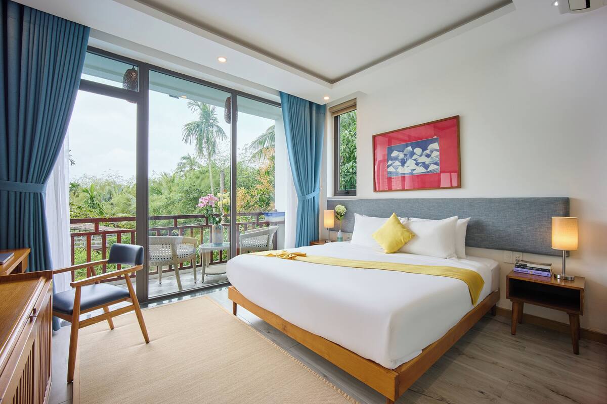 Habitación de hotel con una cama grande, un escritorio, una silla, una mesita de noche y vistas al exterior.