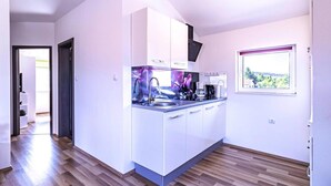 A modern kitchen with white cabinets, a built-in oven, and a window with a view.