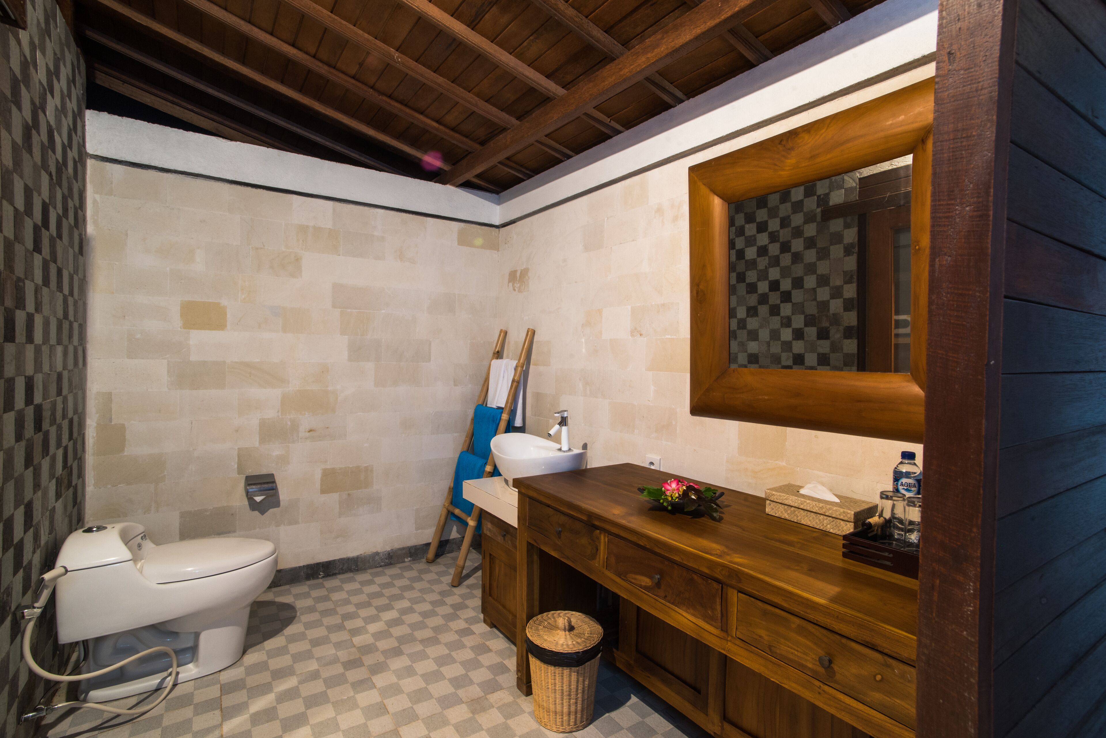 A bathroom with a wooden vanity, a white sink, and a large mirror.