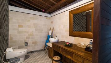 A bathroom with a wooden vanity, a white sink, and a large mirror.