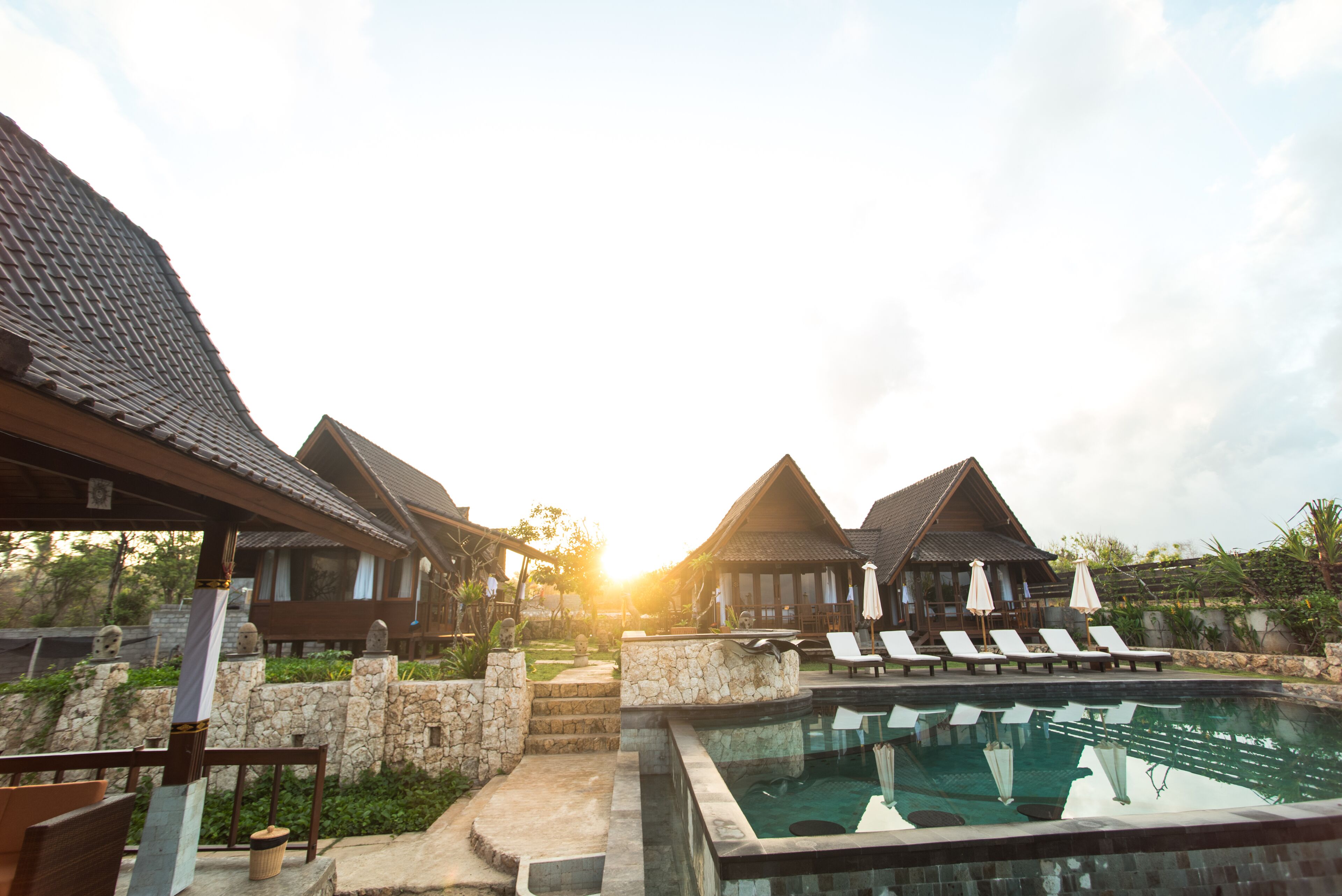 A resort with a swimming pool, lounge chairs, and traditional-style buildings.