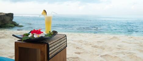 A wooden box with a drink and a flower on a beach.