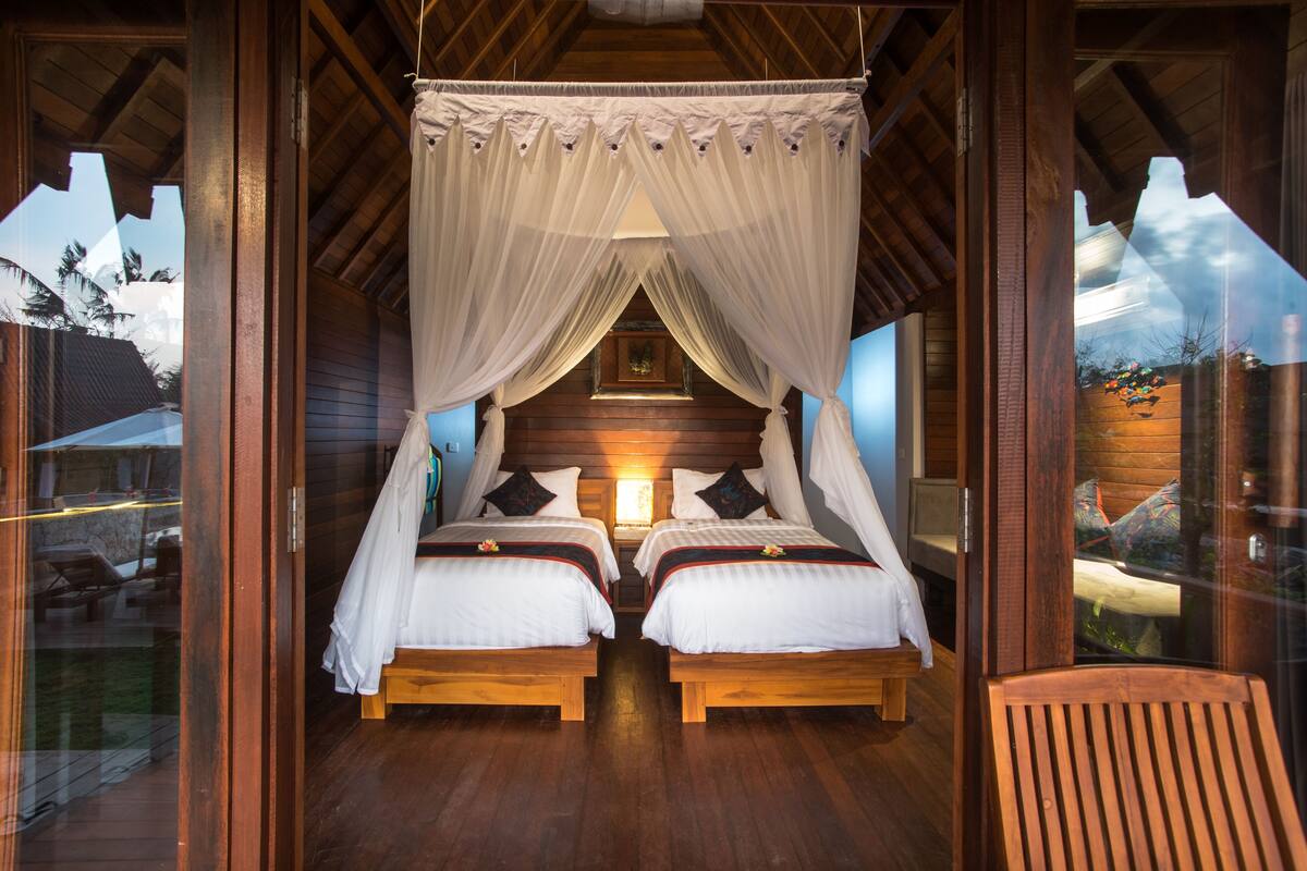 Ein Schlafzimmer mit zwei Betten, Holzboden und einem Himmelbett.