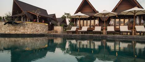Un resort con cabañas de madera, una piscina y tumbonas.