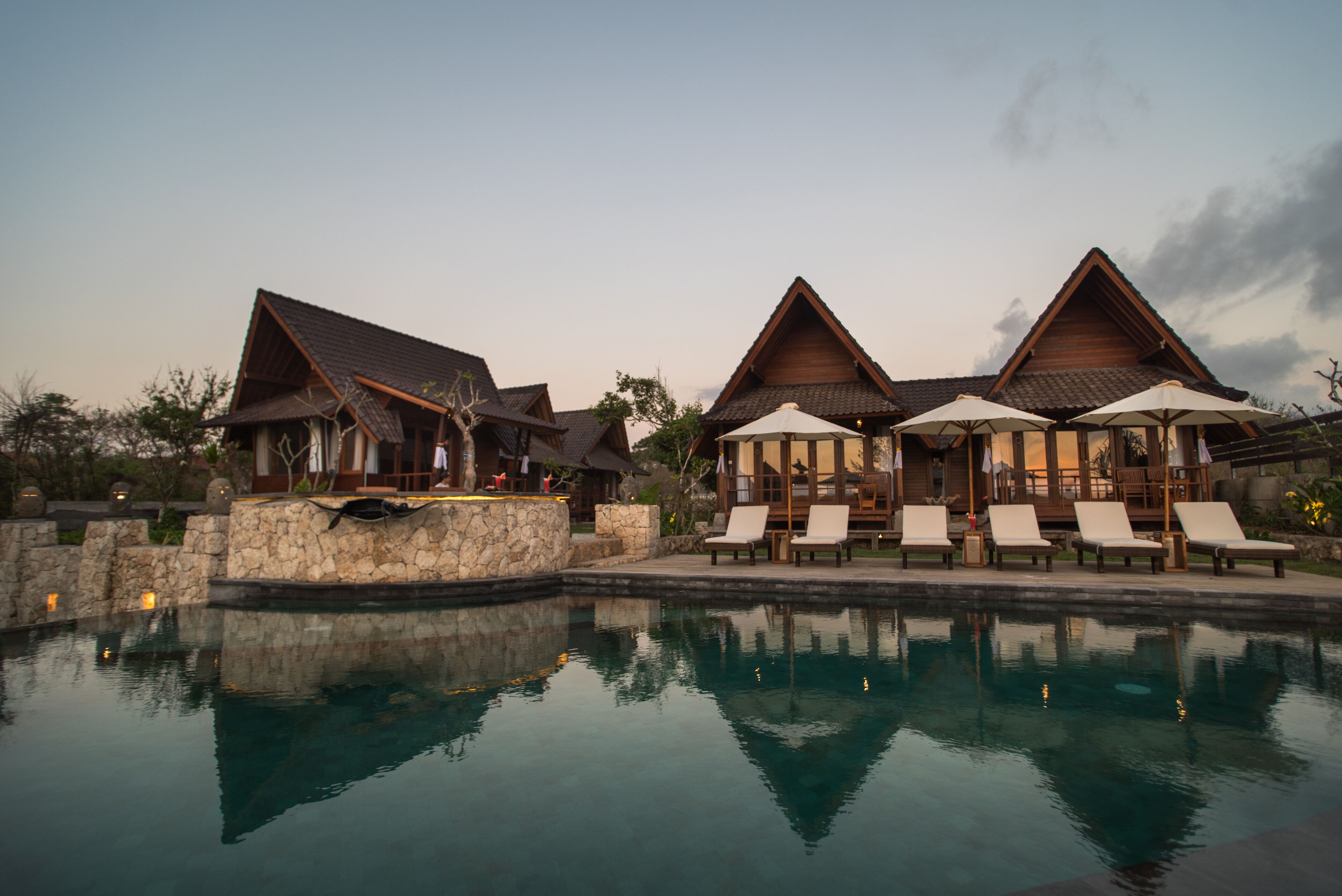 A resort with a pool, lounge chairs, and wooden buildings.