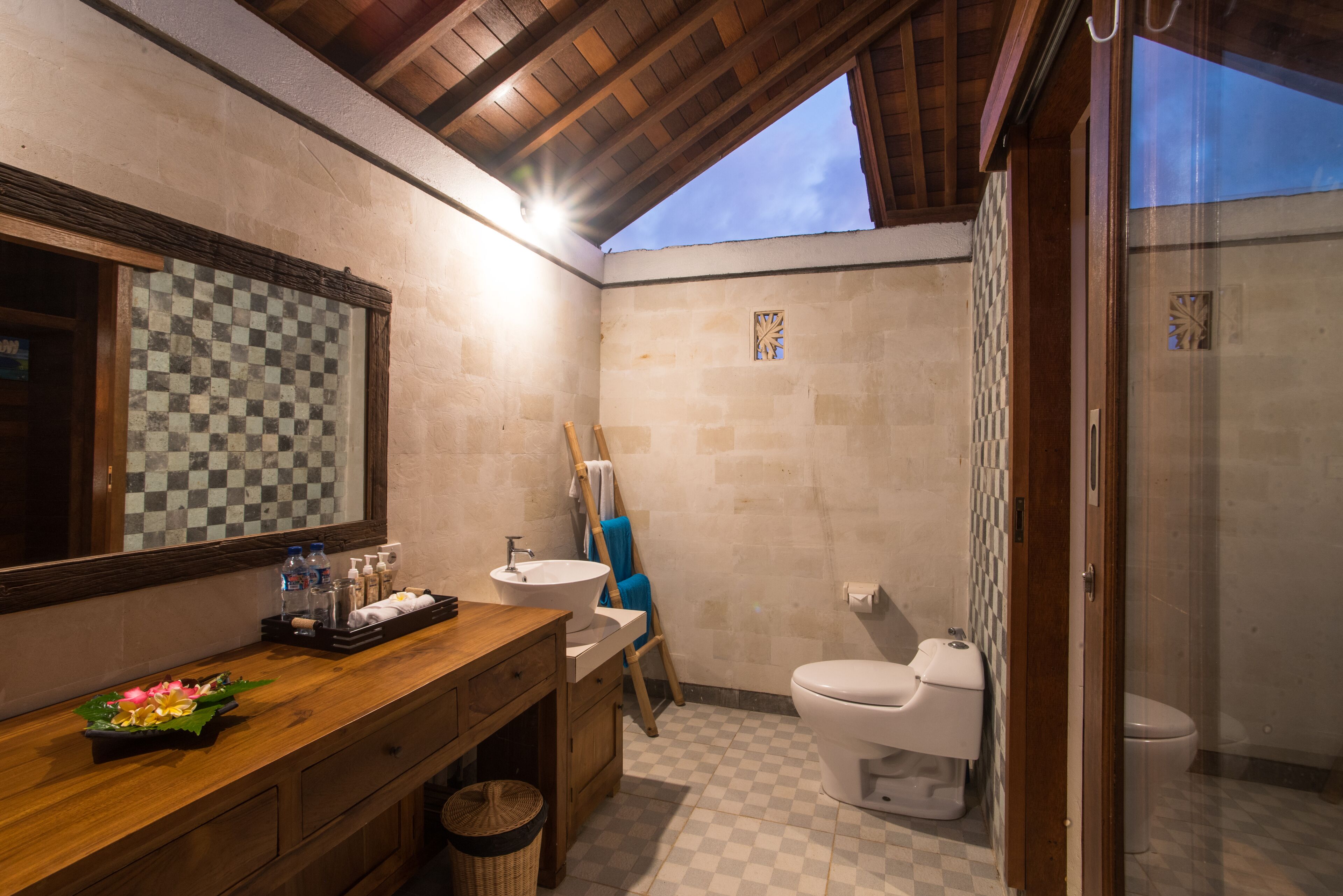 A bathroom with a wooden vanity, a sink, a mirror, and a shower area.