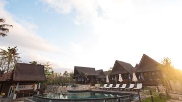 A resort with multiple bungalow-style buildings, a central pool area, and lounge chairs.